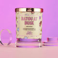 Candle with 'Bayou at Dusk' label on a pink background